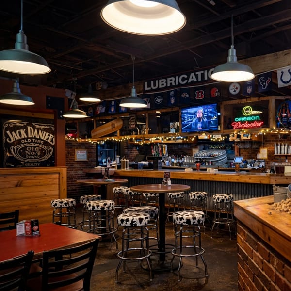 Rustic bar interior with cowhide stools, wooden tables, brick walls, and sports memorabilia.
