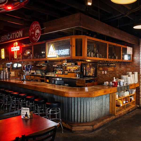 A rustic bar with a wooden counter, metal siding, neon signs, and bar stools.