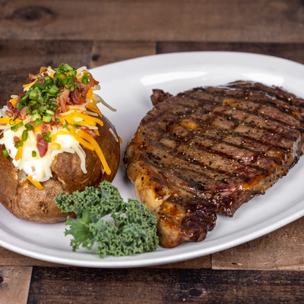 Original Roadhouse Grill steak and loaded baked potato with cheese, bacon, and chives.