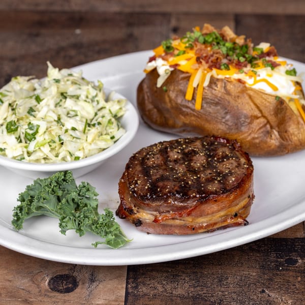 Original Roadhouse Grill steak dinner with bacon-wrapped filet, loaded baked potato, and coleslaw.