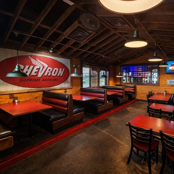 Restaurant interior with red and black booths, red tables, and a large Chevron sign on the wall.